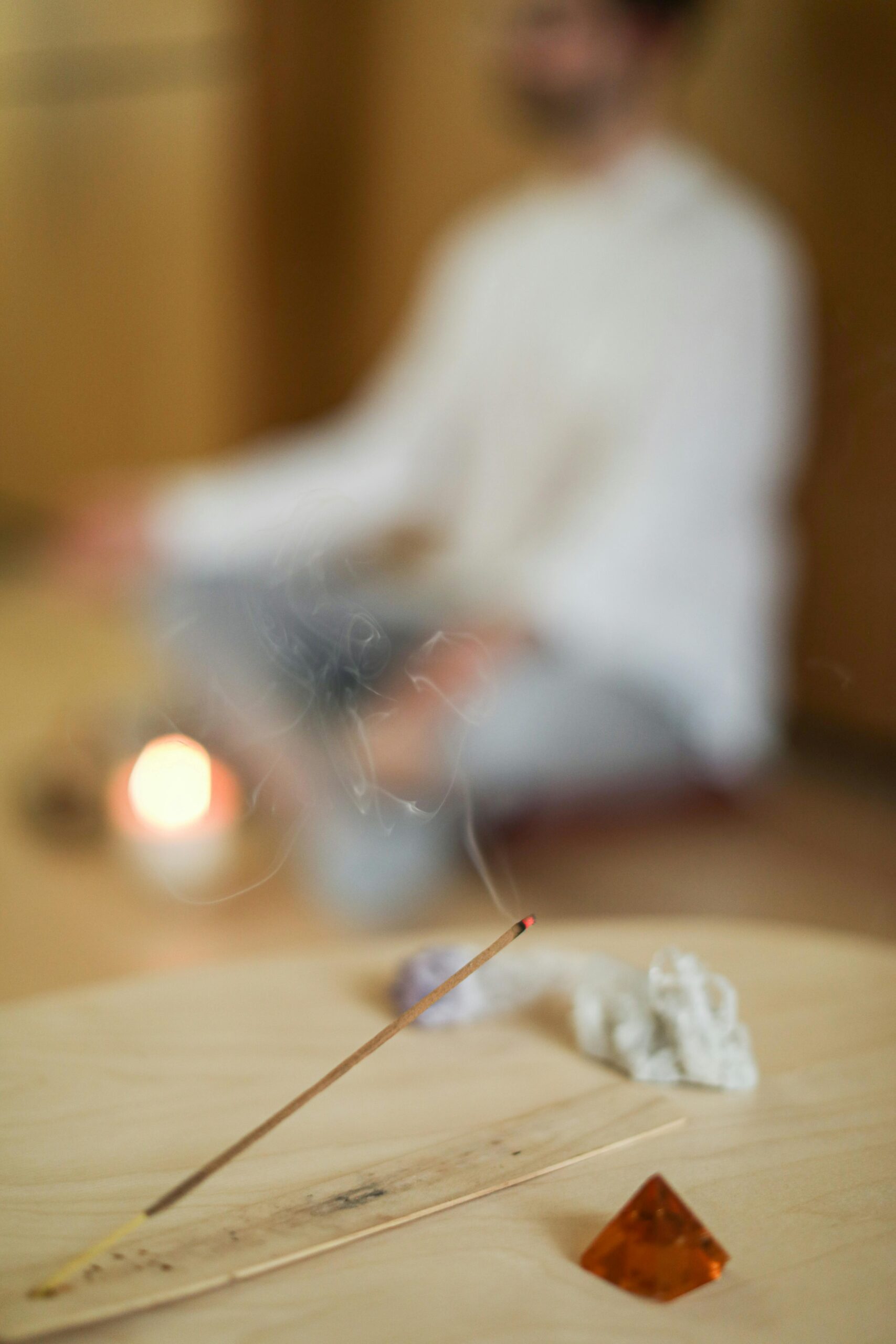 Men sitting in a blurry background, at the front incense is burning